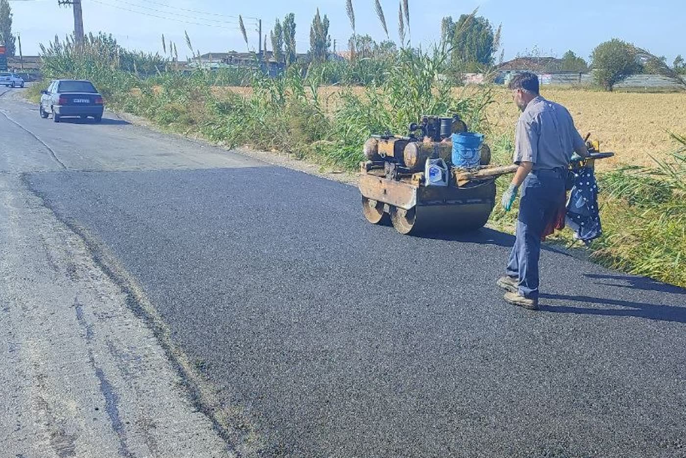 فینیشر در حال پخش آسفالت همراه با اکیپ اجرایی