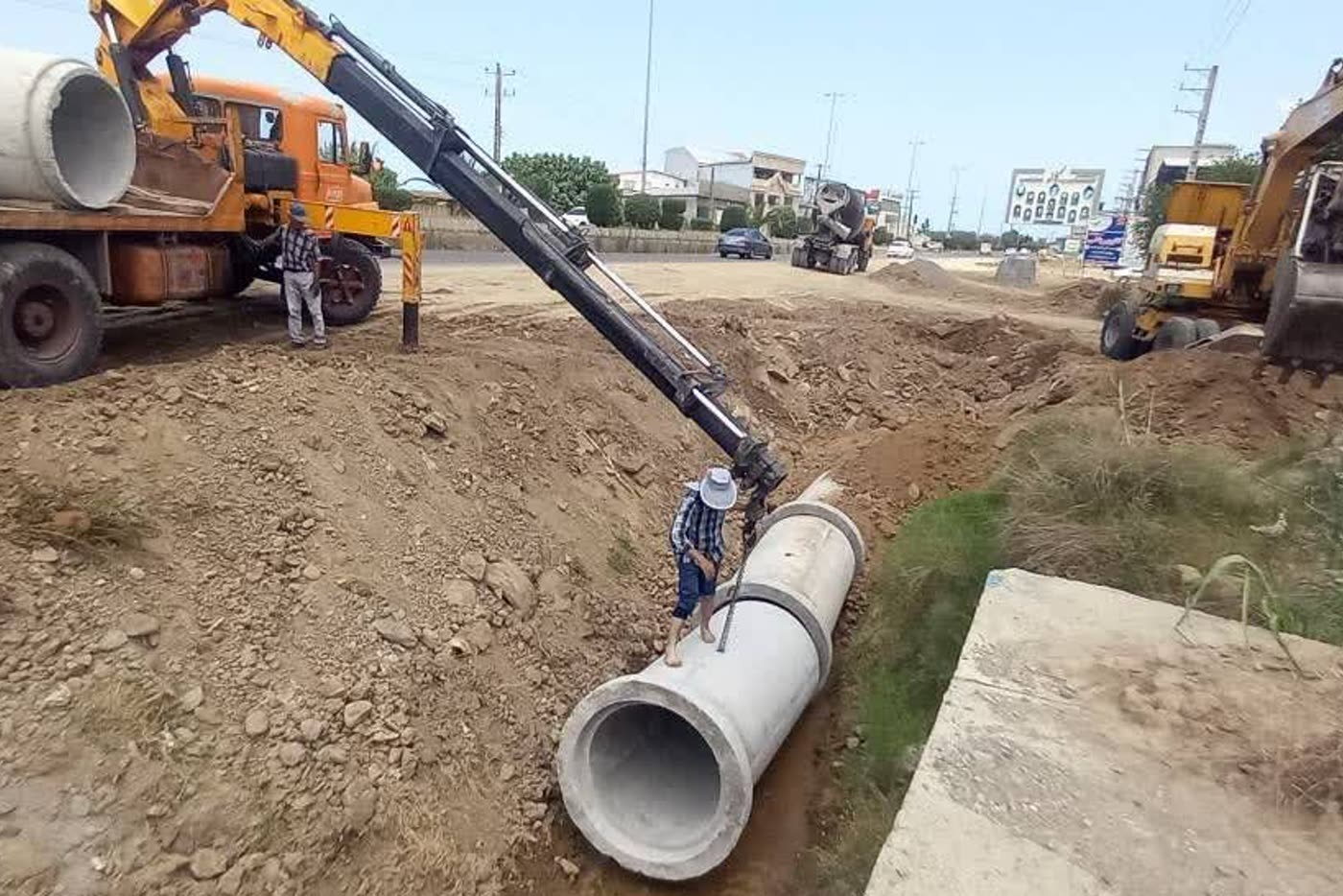 جاگذاری لوله‌های بتنی کانال با جرثقیل در حاشیهٔ راه