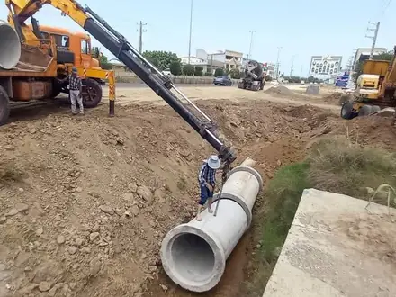 Concrete channel pipes being set with a crane at the roadside