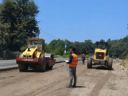 Compacting the base course with two rollers and the grader